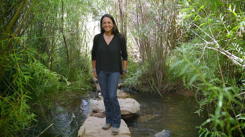 Cristina stands on rocks in a small creek