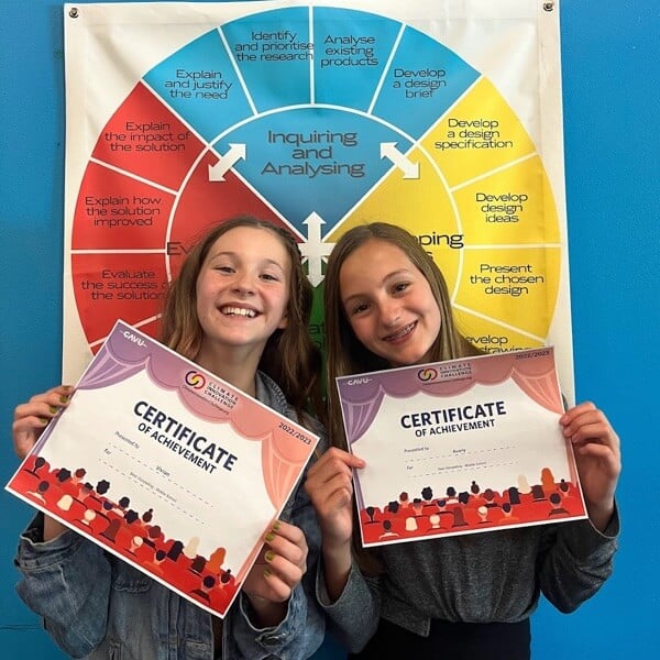 Two girls holding their CAVU climate innovation challenge certificates.