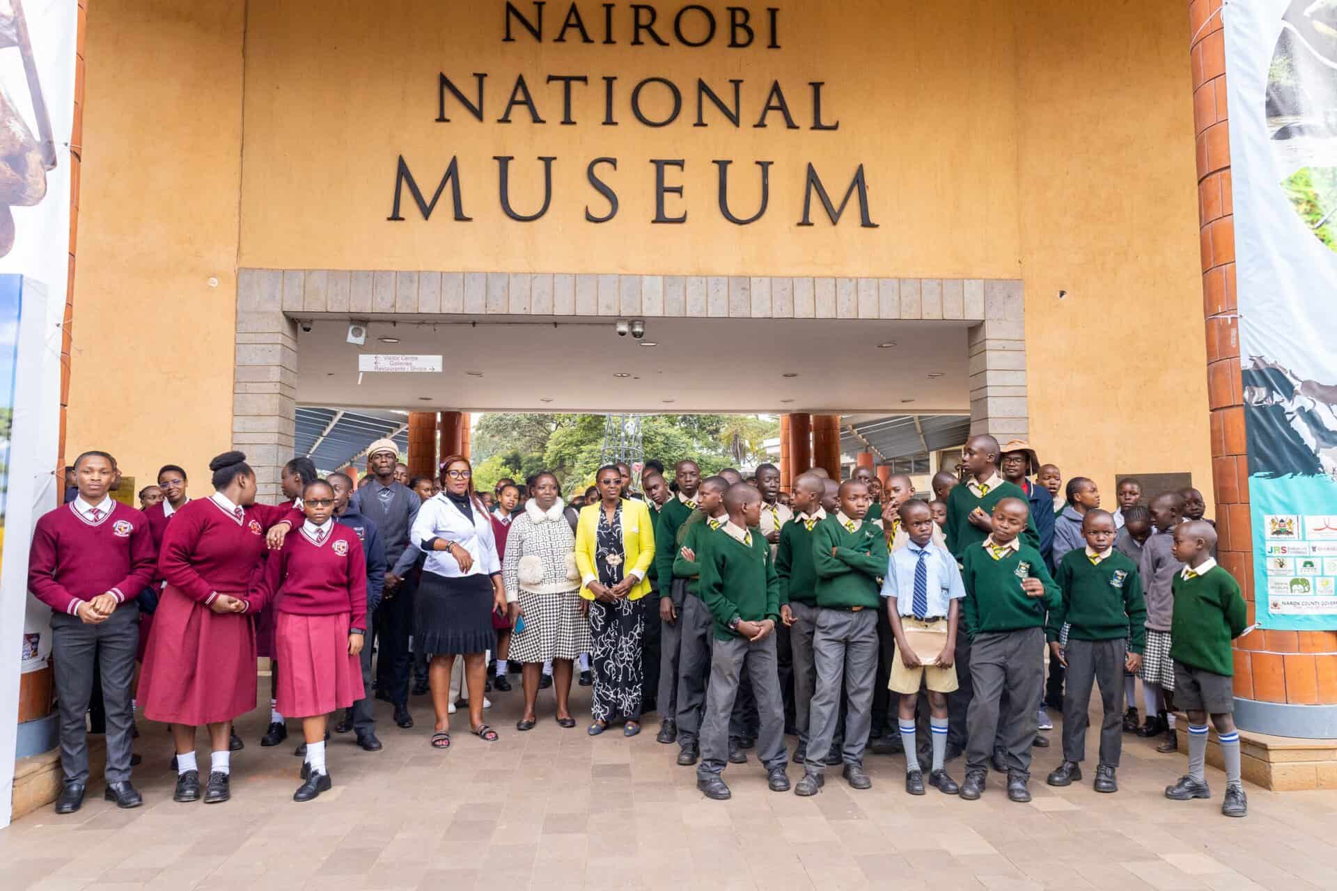 A group of students and adults stand in front of the Nairobi National Museum entrance for a group photo featured in our July 2026 Hope in Action Newsletter.